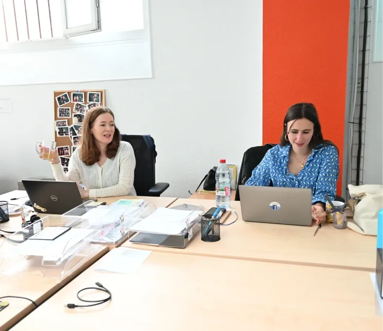 Two Tessan team members working on laptops at a shared desk in the Paris office.