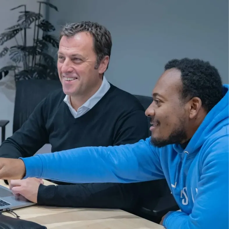 Two Tessan colleagues reviewing work together on a laptop.
